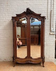 a large wooden armoire sitting in front of a mirror on top of a floor