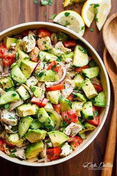 a bowl filled with cucumber, tomato and chicken salad on top of a wooden cutting board