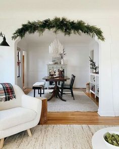 a living room filled with furniture and a christmas wreath hanging from the ceiling over a dining table