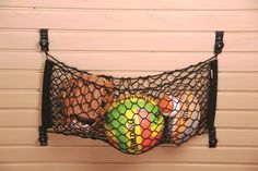 a mesh bag filled with balls hanging on a wall next to a wooden paneled wall