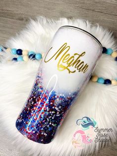 a white and blue cup with gold lettering on it sitting on top of a fur rug