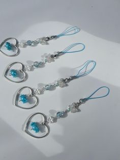 three silver and blue heart shaped earrings on a white surface with one dangling from the ear