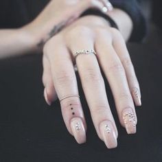 a woman's hand with white and silver nail designs on her nails, sitting in front of a black background