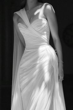 a woman in a white dress and veil posing for a black and white photo with her hands on her hips