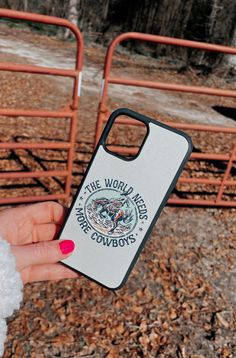 someone holding up their phone case in front of some metal railings and snow on the ground