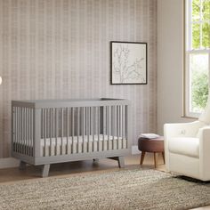 a living room with a white chair and a baby crib in the corner next to a window