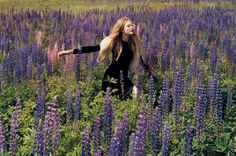 a woman standing in a field of purple flowers