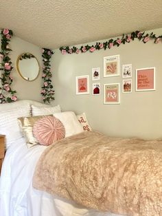 a bedroom with pink flowers on the wall and pictures above the bed, along with other decorations