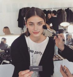 a woman is getting her make up done in front of a mirror and another person