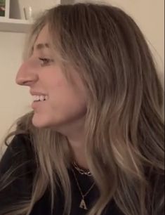 a woman with long hair is smiling and looking off into the distance while wearing a black shirt