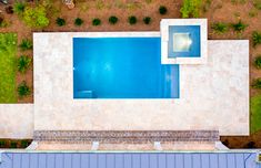 an aerial view of a swimming pool in the middle of a yard with trees and shrubs