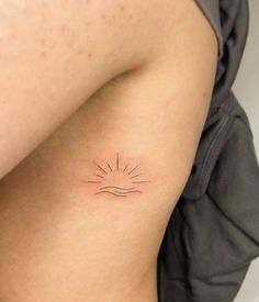 a woman's arm with a small sun tattoo on the back of her shoulder