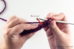 two hands crocheting the end of a purple yarn ball with an orange hook