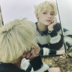 a woman with blonde hair looking at herself in the mirror