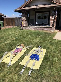 two skeletons laying on towels in front of a house