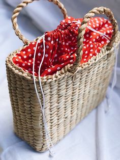 a wicker basket with red and white polka dot fabric in it sitting on a bed