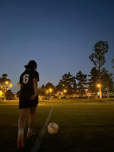 a person standing on a field with a soccer ball in front of them at night