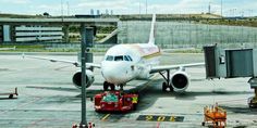 an airplane is parked on the tarmac with its luggage cart in front of it