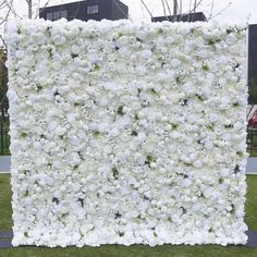 a large white flower covered wall in the grass