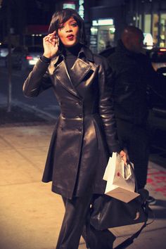 a woman walking down the street talking on her cell phone and holding a shopping bag