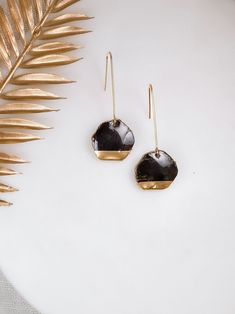 Introducing the Obsidian Luster Drops: a bold statement from Sydney Jane Jewelry's exquisite Corcelain Collection. These earrings fuse the enigmatic allure of obsidian with the timeless sheen of gold, creating an accessory that is as captivating as it is elegant. Each piece is a homage to the volcanic grace of natural obsidian, paired with the sophistication of polished porcelain, reminiscent of the night sky's mystic beauty. Handcrafted with precision, these earrings reflect the brand's commitment to sustainable luxury and ethical fashion. Ideal for any occasion, the Obsidian Luster Drops are a celebration of dark beauty and radiant design, perfect for the discerning individual who carries a love for the profound and the refined. Sustainable Jewelry, Dark Beauty, Ethical Fashion, Chandelier Earrings, Sydney, Handmade Items, Porcelain, Craft Supplies, Handmade Gifts