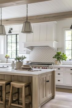 a kitchen with two stools in front of an island and three lights hanging from the ceiling