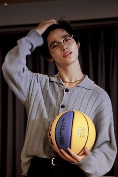 a woman holding a basketball in her right hand and posing for the camera with one hand on her head