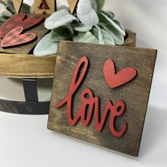 two wooden signs with the word love painted on them next to some succulents