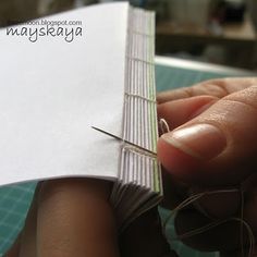 a person is holding a piece of paper with some scissors in it and thread on the edge