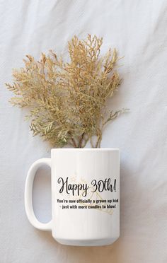 a coffee mug with a plant in it on a white tablecloth that says happy 30th