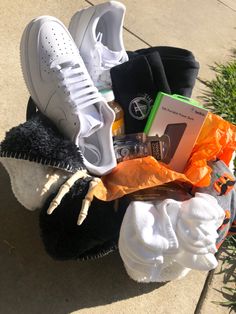 an assortment of shoes and socks sitting on top of a pile of clothing next to a plant