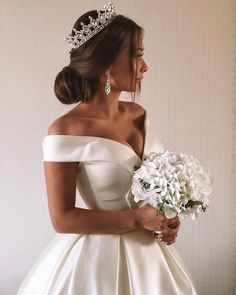 a woman in a wedding dress holding a bouquet and wearing a tiara on her head