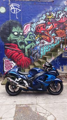 a blue motorcycle parked in front of a graffiti covered wall