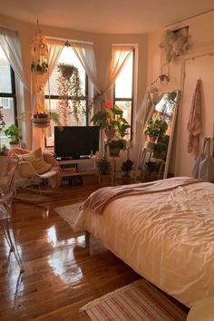 a bedroom with hardwood floors and lots of plants in the window sill, along with a bed