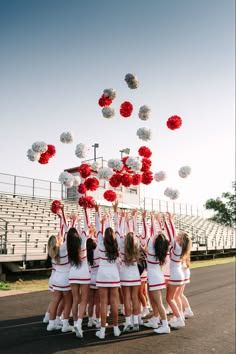 a group of cheerleaders in white and red outfits are throwing pom - poms into the air