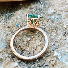 a gold ring with a green stone in the center on top of a marble surface