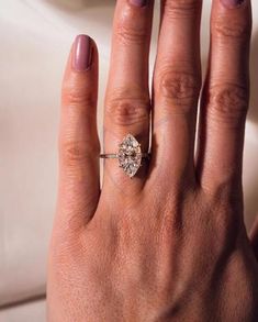 a woman's hand with a ring on it and a diamond in the middle