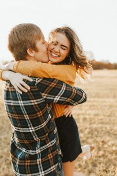 a young man and woman embracing each other in an open field