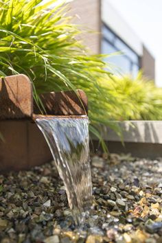 a water fountain spewing out from the ground in front of a planter