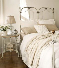 a bedroom with green walls and white bedding in the center is a small table with flowers on it