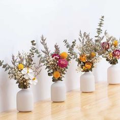 four white vases filled with different types of flowers