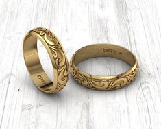 two gold wedding rings sitting next to each other on a white wooden surface with the word dry written in it