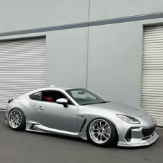 a silver sports car parked in front of a garage door