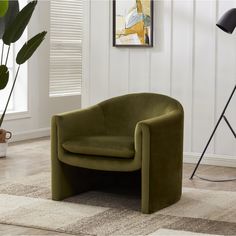 a green chair sitting on top of a wooden floor next to a potted plant