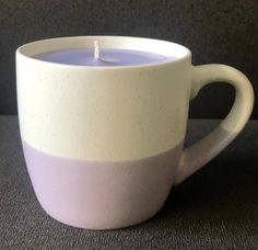 a white coffee cup with a lit candle in it