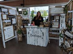 a woman standing behind a counter in front of many wooden signs and other items on display