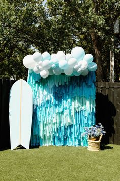 a surfboard is next to a backdrop made out of plastic bottles and streamers