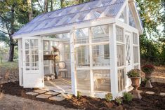 a small white house sitting in the middle of a forest