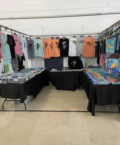 there are many t - shirts on display in the store with black tablecloths