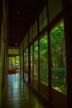 an empty hallway with lots of windows and doors leading to the trees in the yard